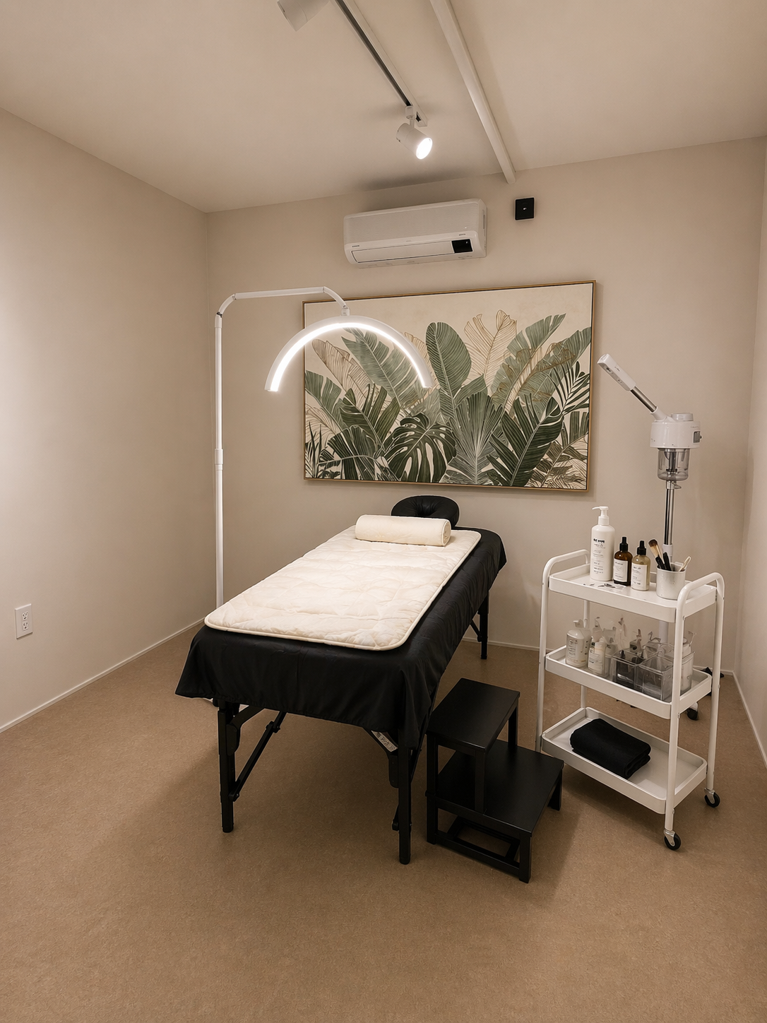 Facial & Waxing studio: a treatment bed with an arch ring light, esthetics cart, facial steamer, and botanical wall art
