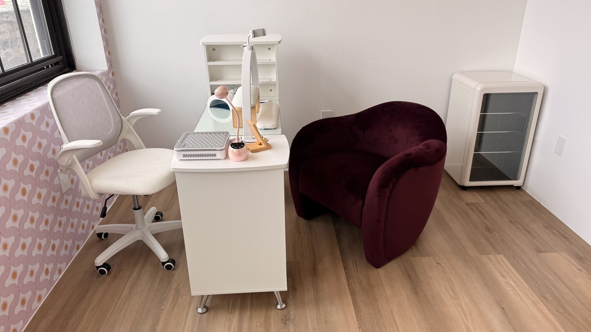 Nail Studio: white manicure desk with gel lamp and dust extractor, pink-orange accent wall, burgundy velvet armchair for the client.