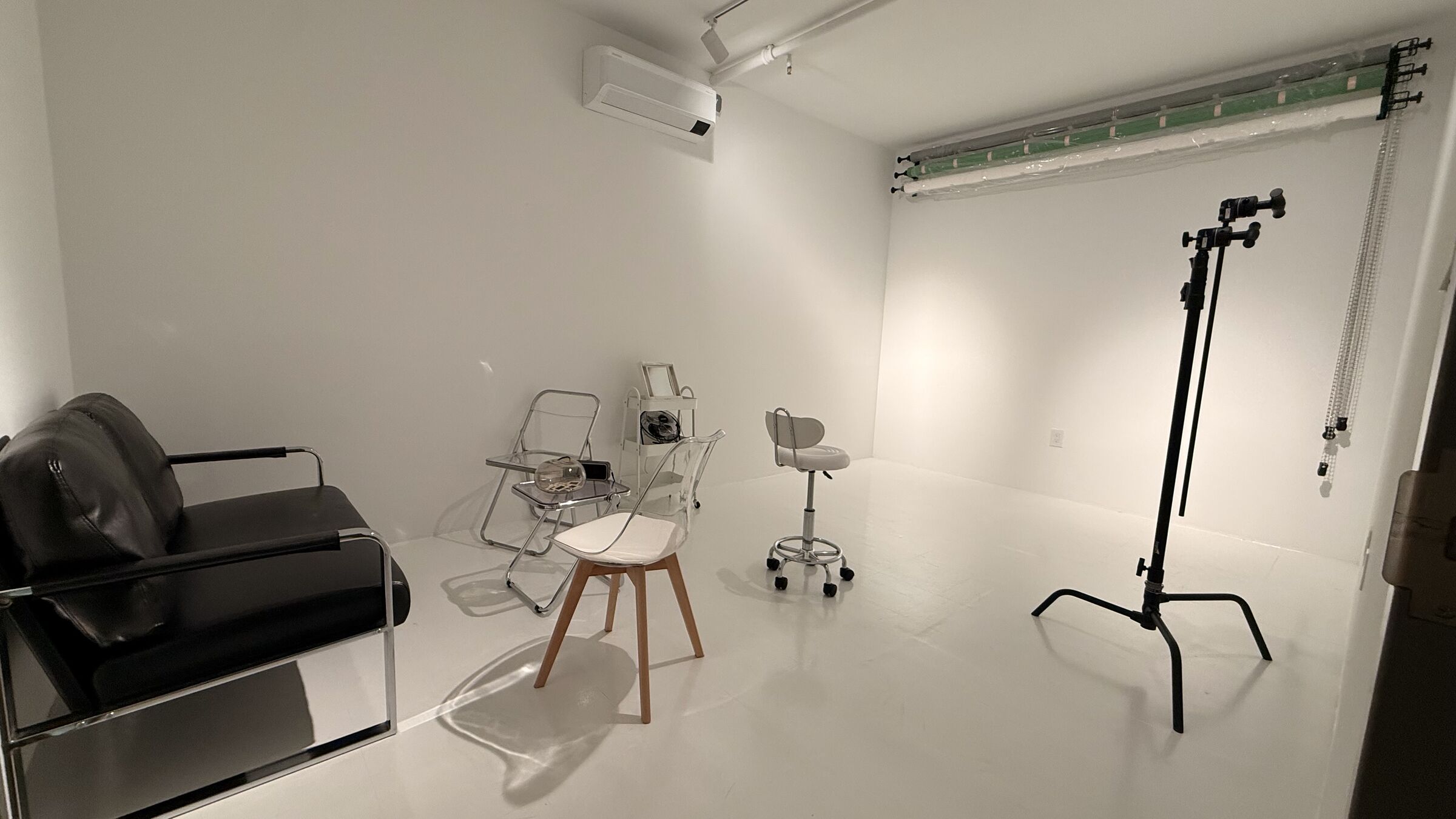 Portrait Studio with white seamless backdrop, C-stand, black leather couch and Brooklyn-light styling